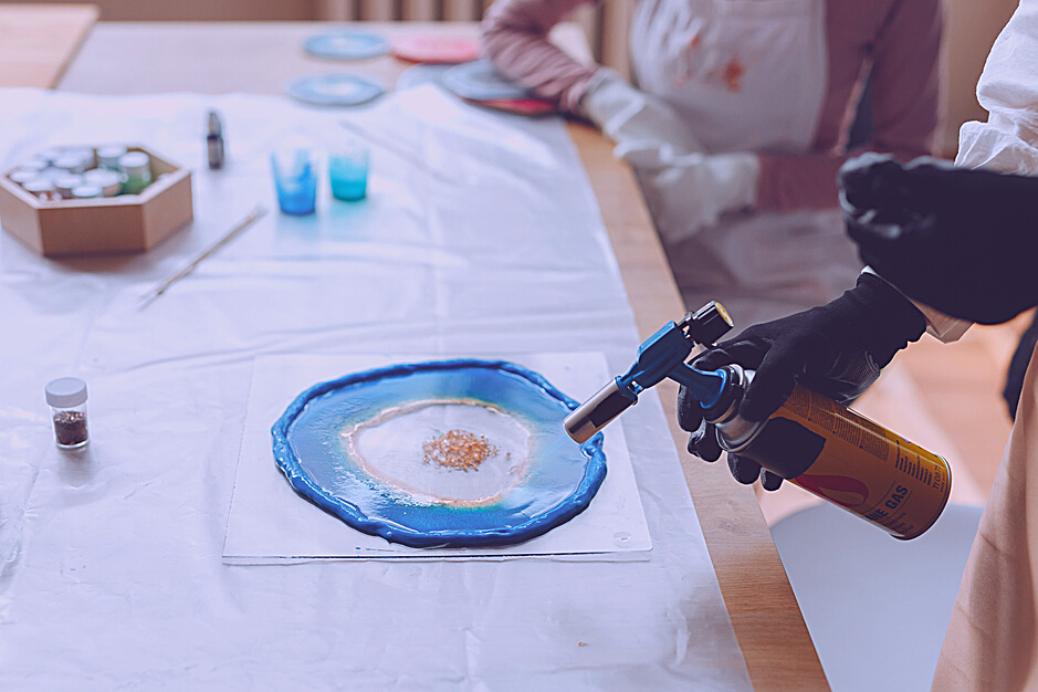 Person Holding a Gas Burner to a Resin Art Project